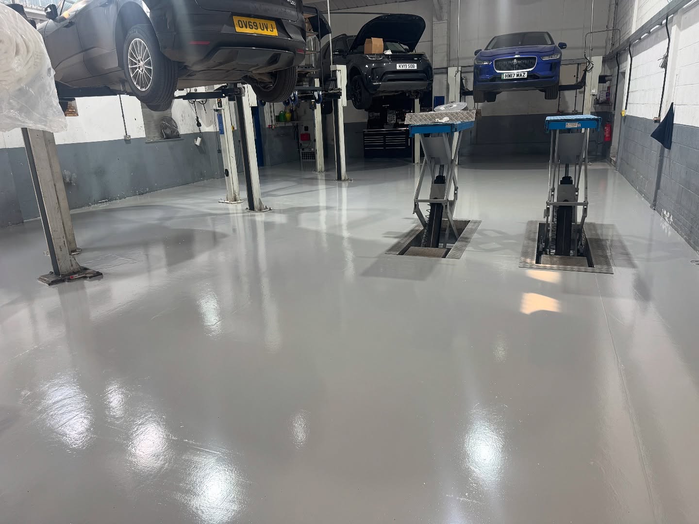 Car garage with vehicles on lifts and epoxy floor