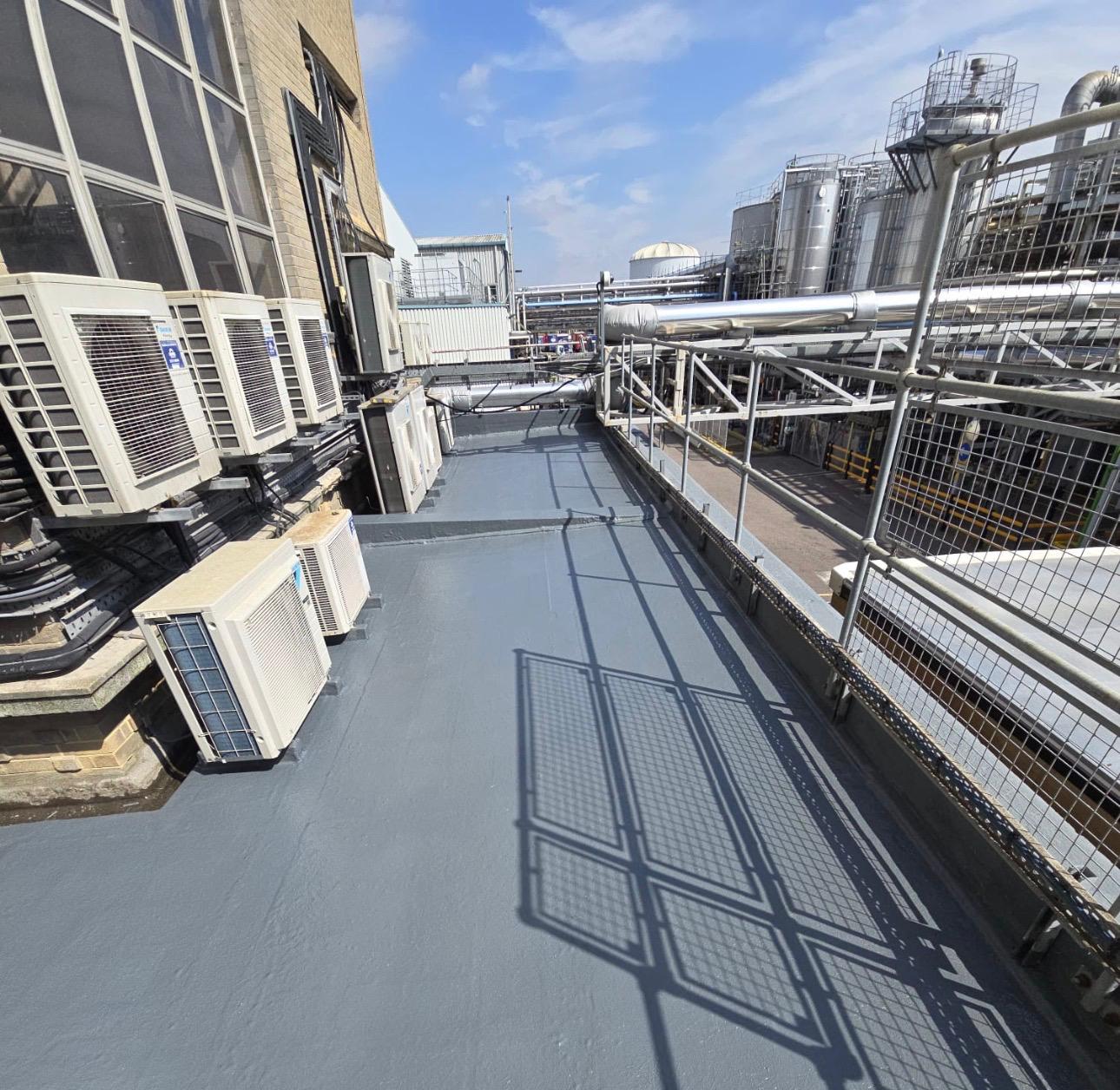 Completed flat roof coating with plant tanks beyond